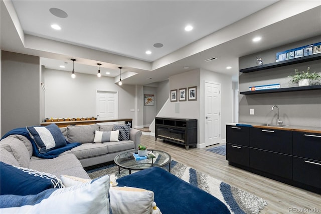 7106 Cerney Cir, Castle Pines, CO 80108 - living area featuring wet bar, baseboards, light wood-style floors, a tray ceiling, and recessed lighting