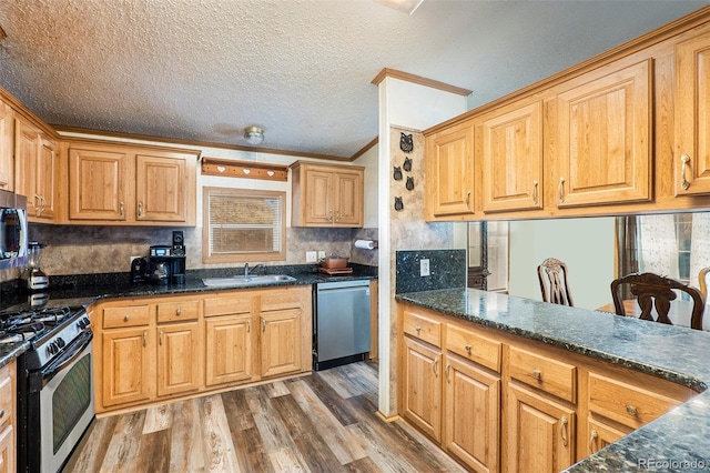 kitchen featuring appliances with stainless steel finishes, sink, hardwood / wood-style flooring, crown molding, and a textured ceiling