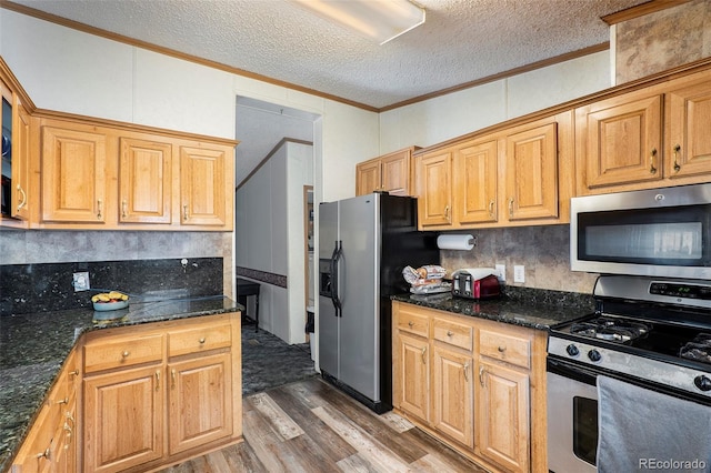 kitchen with hardwood / wood-style flooring, stainless steel appliances, ornamental molding, a textured ceiling, and dark stone counters