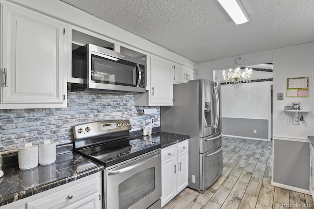 kitchen featuring a notable chandelier, appliances with stainless steel finishes, light hardwood / wood-style flooring, and white cabinetry