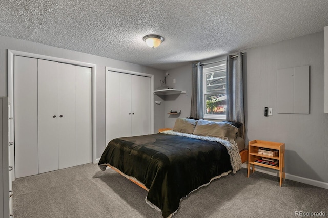 carpeted bedroom with multiple closets and a textured ceiling