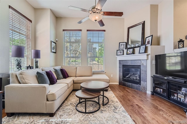 living room with a fireplace, ceiling fan, and wood-type flooring