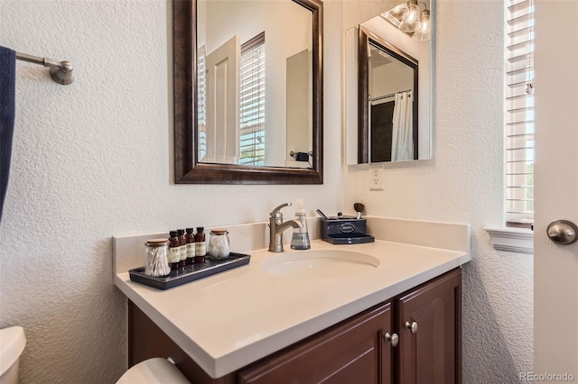 bathroom with toilet, plenty of natural light, and vanity