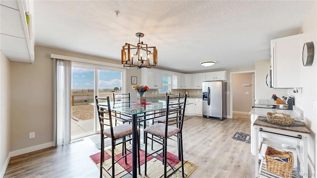 32350 E 137th Way, Brighton, CO 80603 - dining room featuring light wood-style floors, a chandelier, baseboards, and a textured ceiling