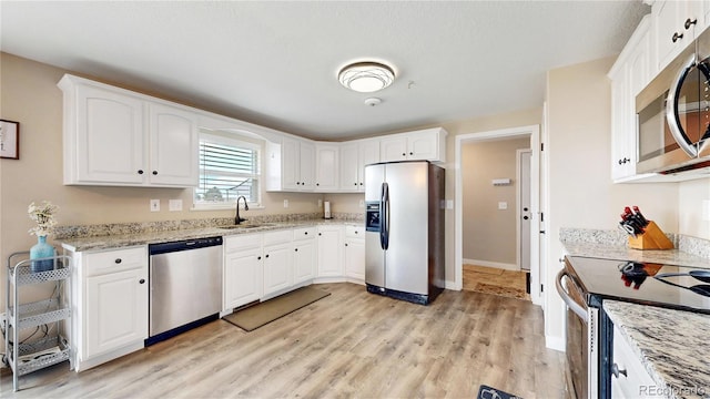 32350 E 137th Way, Brighton, CO 80603 - kitchen with stainless steel appliances, a sink, light wood-type flooring, white cabinets, and light stone countertops