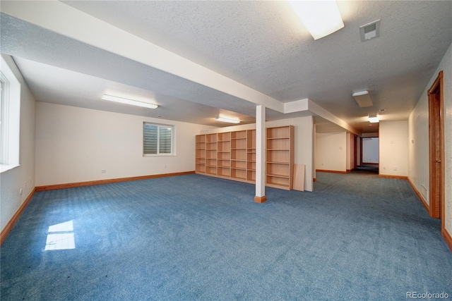 basement featuring dark colored carpet and a textured ceiling