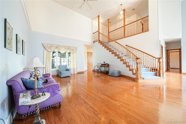 living room featuring ceiling fan, wood-type flooring, and a high ceiling