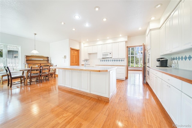 kitchen with sink, hanging light fixtures, light wood-type flooring, white appliances, and white cabinets