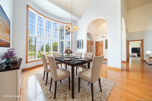 dining area featuring a notable chandelier, high vaulted ceiling, and light hardwood / wood-style flooring