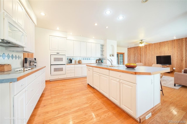 kitchen featuring sink, a breakfast bar area, a kitchen island, white appliances, and white cabinets