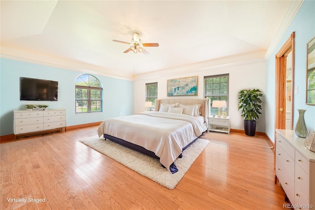 bedroom featuring crown molding, ceiling fan, a tray ceiling, and light hardwood / wood-style flooring