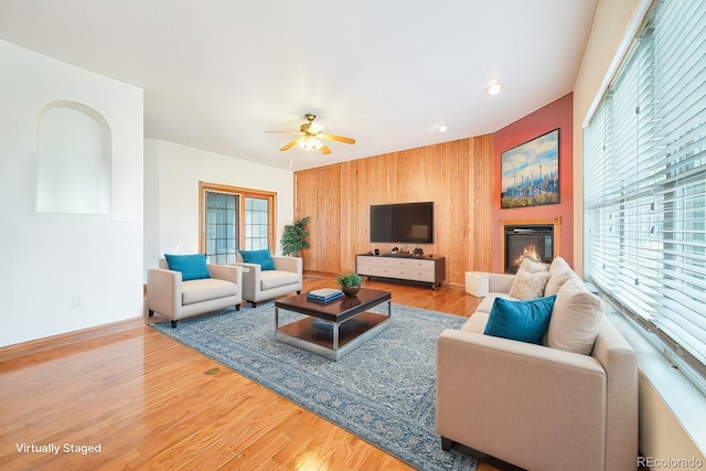 living room with a wealth of natural light, wooden walls, and light hardwood / wood-style flooring