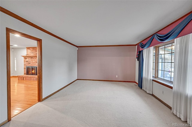 spare room with a brick fireplace, carpet floors, and ornamental molding