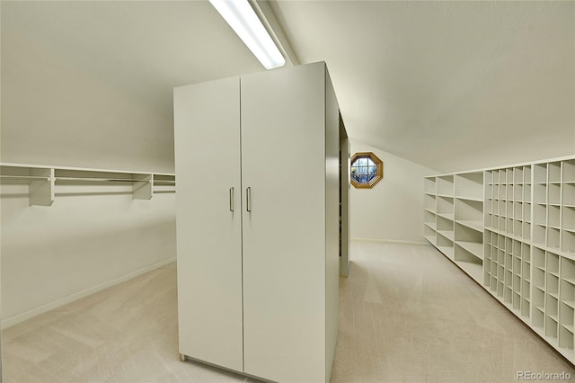 walk in closet with light carpet and lofted ceiling