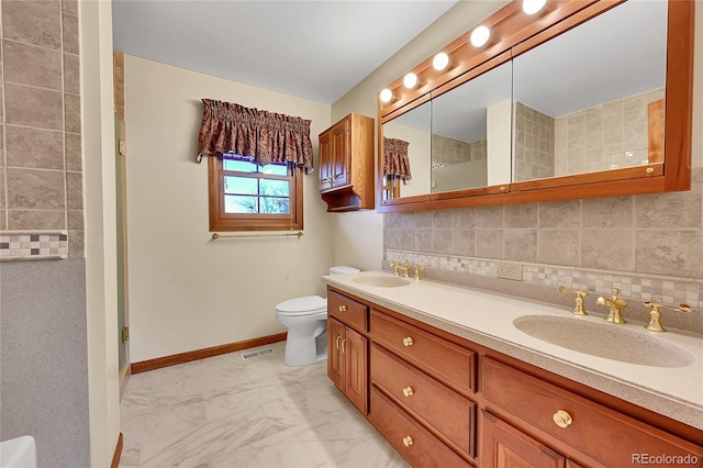 bathroom featuring vanity, toilet, a shower, and tasteful backsplash