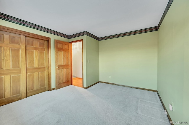 unfurnished bedroom with light colored carpet, a closet, and crown molding