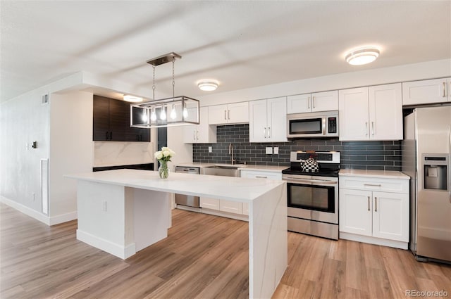 2 Adams St Unit 1504, Denver, CO 80206 - kitchen with appliances with stainless steel finishes, a kitchen island, light countertops, white cabinets, and light wood-style floors
