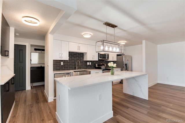 2 Adams St Unit 1504, Denver, CO 80206 - kitchen featuring appliances with stainless steel finishes, a center island, backsplash, wood finished floors, and white cabinets