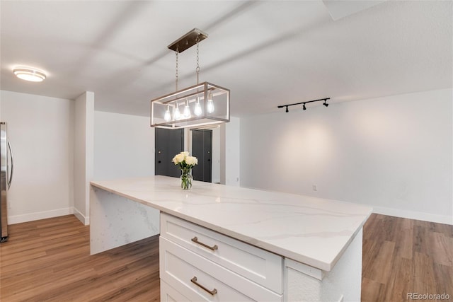 2 Adams St Unit 1504, Denver, CO 80206 - kitchen with light wood-type flooring, white cabinetry, light stone countertops, decorative light fixtures, and freestanding refrigerator