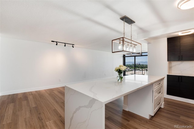 2 Adams St Unit 1504, Denver, CO 80206 - kitchen featuring wood finished floors, a center island, pendant lighting, and light stone countertops