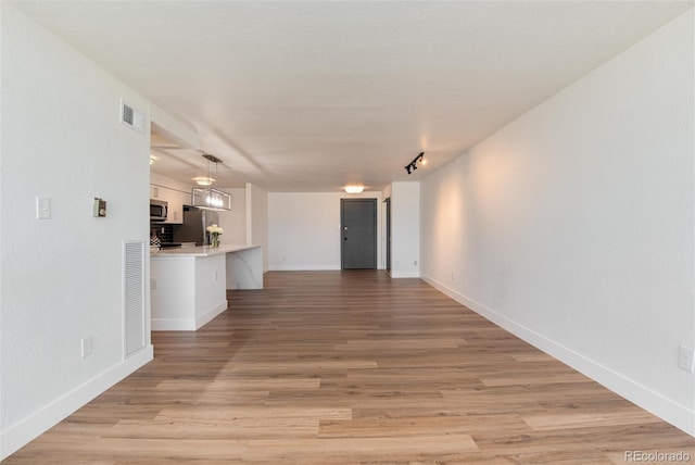 2 Adams St Unit 1504, Denver, CO 80206 - unfurnished living room featuring light wood-style floors and rail lighting