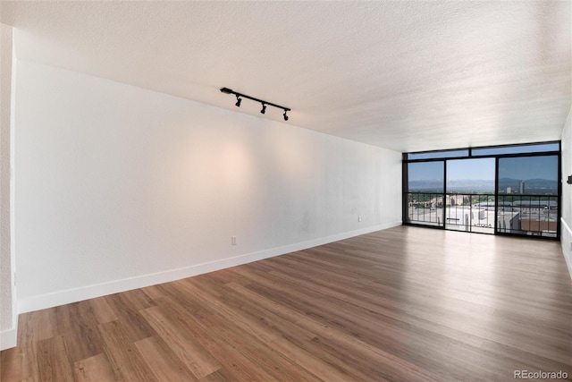 2 Adams St Unit 1504, Denver, CO 80206 - unfurnished room with wood finished floors, rail lighting, a textured ceiling, and floor to ceiling windows