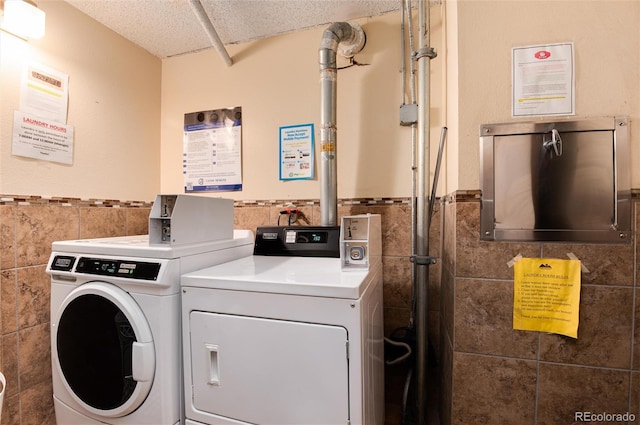 2 Adams St Unit 1504, Denver, CO 80206 - shared laundry room with tile walls, washer and dryer, a wainscoted wall, and a textured ceiling