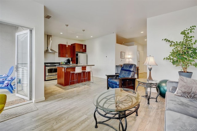 living area featuring baseboards, light wood-style floors, visible vents, and recessed lighting