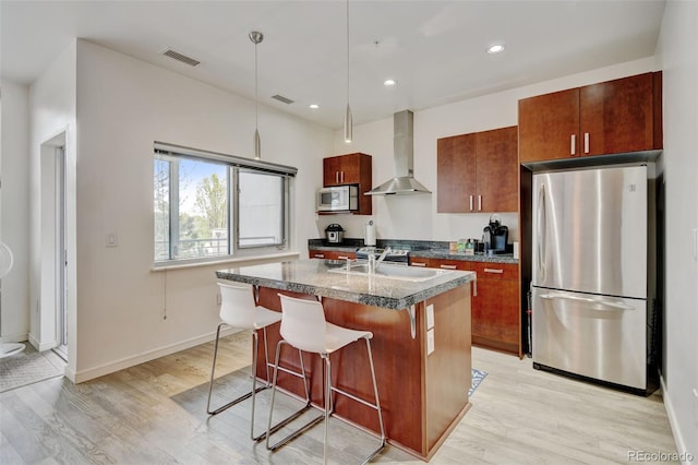 kitchen with a sink, white microwave, freestanding refrigerator, visible vents, and wall chimney exhaust hood