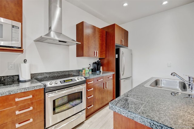 kitchen with recessed lighting, a sink, wall chimney exhaust hood, tile counters, and appliances with stainless steel finishes