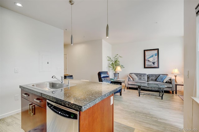 kitchen with light wood finished floors, brown cabinets, a sink, open floor plan, and stainless steel dishwasher