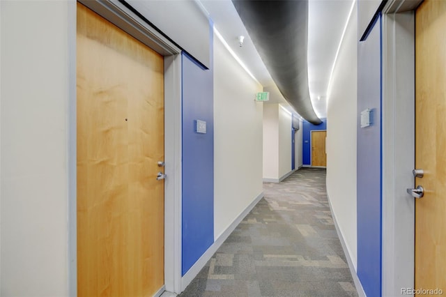 hallway with baseboards and light carpet