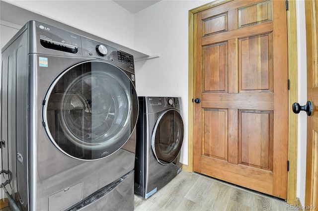 washroom featuring laundry area, washing machine and dryer, and light wood finished floors