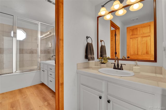 bathroom featuring enclosed tub / shower combo, visible vents, vanity, and wood finished floors