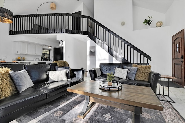 living area featuring light tile patterned floors, stairway, and a high ceiling