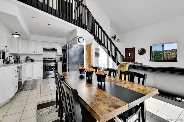 dining space with light tile patterned floors, visible vents, a high ceiling, recessed lighting, and stairs