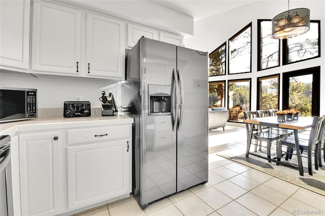 kitchen with light tile patterned floors, white cabinets, stainless steel appliances, and light countertops