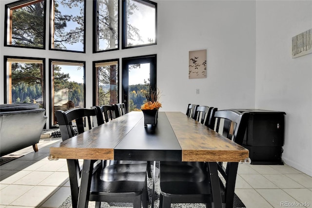 dining area with light tile patterned floors and a towering ceiling