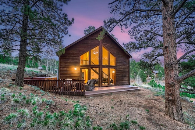 back of house at dusk featuring a wooden deck