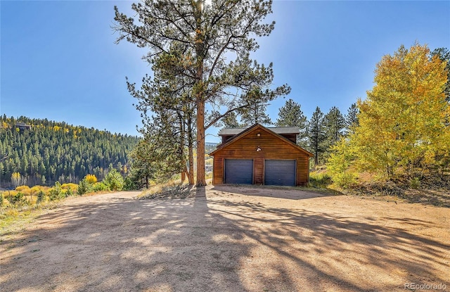 detached garage with a view of trees