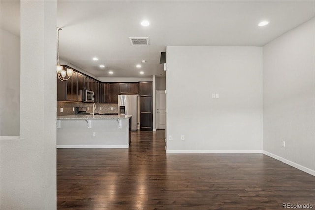 15492 W 65th Ave Unit C, Arvada, CO 80007 - kitchen featuring appliances with stainless steel finishes, dark brown cabinets, dark wood-style flooring, a breakfast bar, and a peninsula