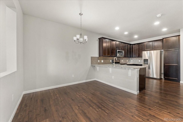15492 W 65th Ave Unit C, Arvada, CO 80007 - kitchen featuring appliances with stainless steel finishes, a peninsula, tasteful backsplash, dark brown cabinetry, and a breakfast bar area