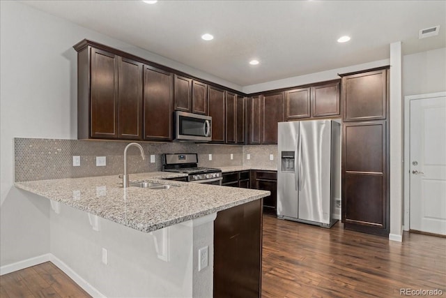 15492 W 65th Ave Unit C, Arvada, CO 80007 - kitchen with stainless steel appliances, a peninsula, light stone countertops, dark brown cabinetry, and dark wood finished floors