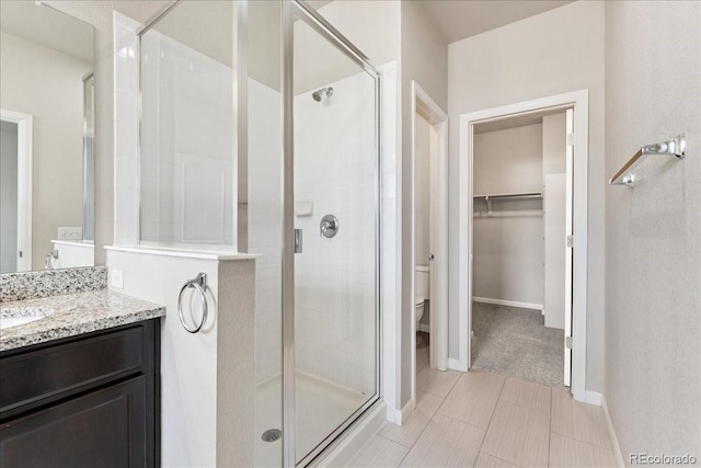 15492 W 65th Ave Unit C, Arvada, CO 80007 - bathroom featuring a stall shower, vanity, a walk in closet, and tile patterned flooring