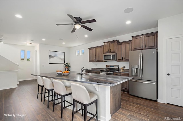 19096 E 55th Ave, Denver, CO 80249 - kitchen featuring appliances with stainless steel finishes, a sink, a center island with sink, ceiling fan, and dark brown cabinets