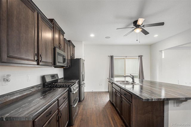 19096 E 55th Ave, Denver, CO 80249 - kitchen with stainless steel appliances, a sink, dark countertops, dark brown cabinets, and ceiling fan