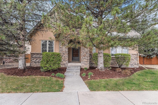 view of front of home featuring stone siding, stucco siding, and fence