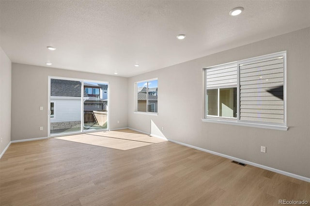 spare room featuring light hardwood / wood-style flooring and a textured ceiling