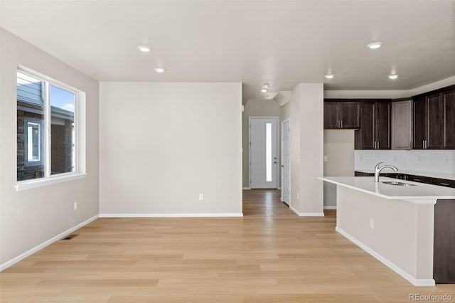 kitchen featuring dark brown cabinetry, sink, backsplash, and light hardwood / wood-style floors