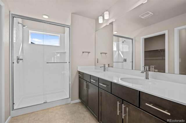 bathroom with walk in shower, vanity, and tile patterned flooring